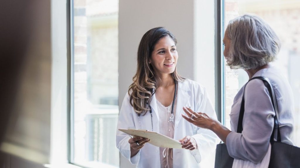 A doctor and a patient discussing factors to consider when choosing between osteopathy and physiotherapy